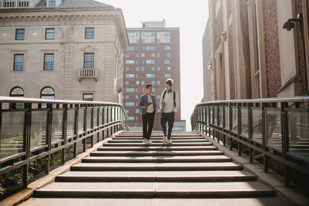 Deux jeunes hommes qui discutent sur un pont entouré d’immeubles
